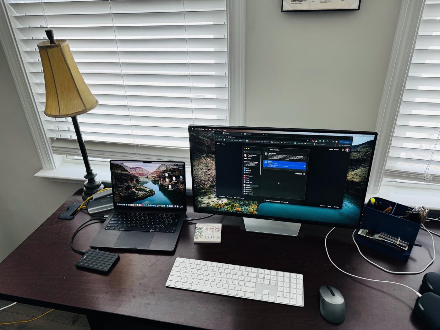 A real new-computer setup with laptop, monitor, external drives, and migration equipment