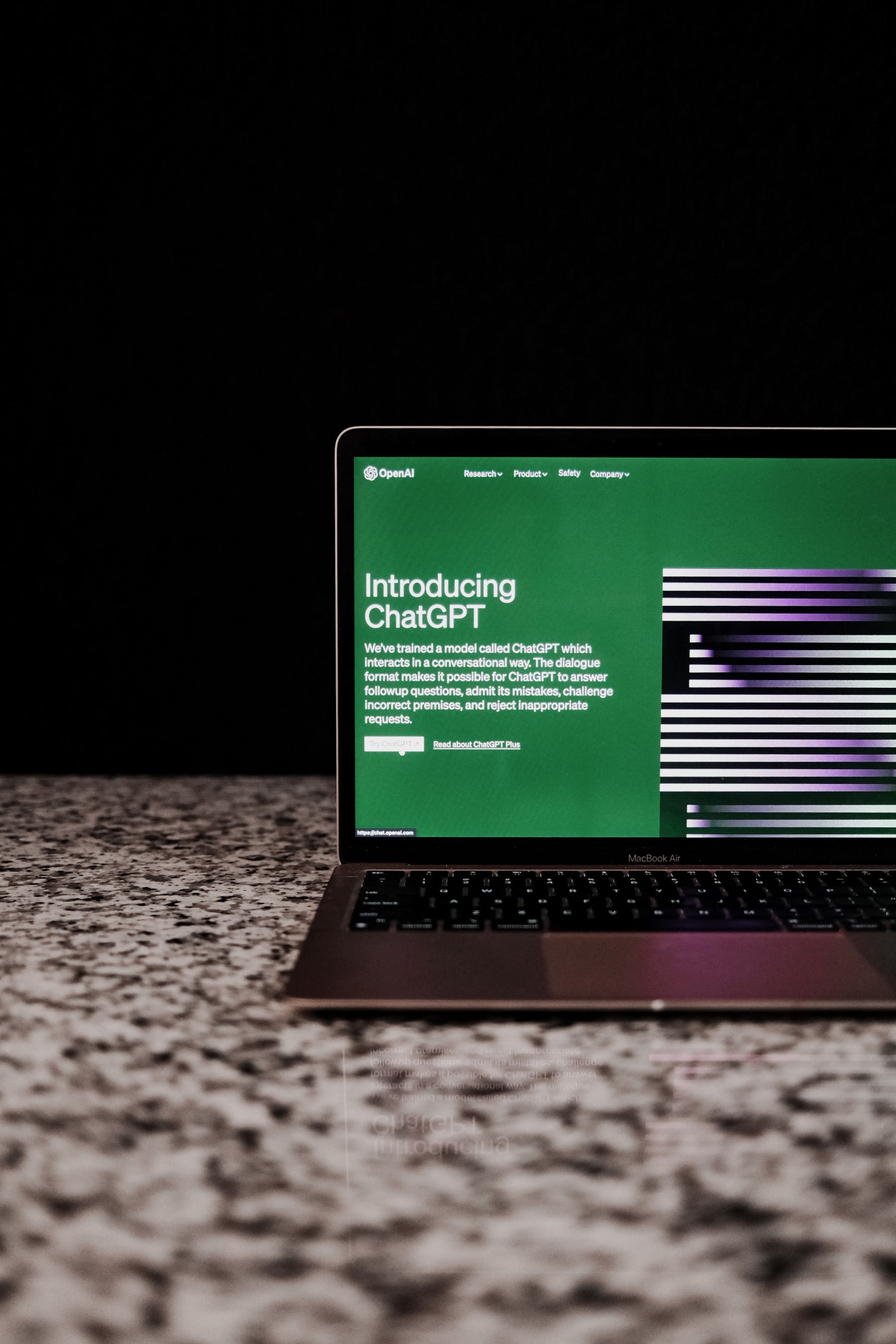 Real laptop displaying the ChatGPT website on a stone countertop